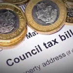 UK council tax bill with pound coins placed on top of the document