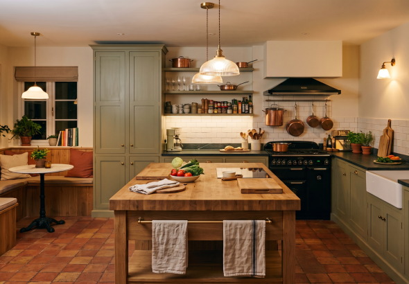 Cosy kitchen with wooden island, vegetables, copper pans, and a breakfast nook with plants and natural lighting